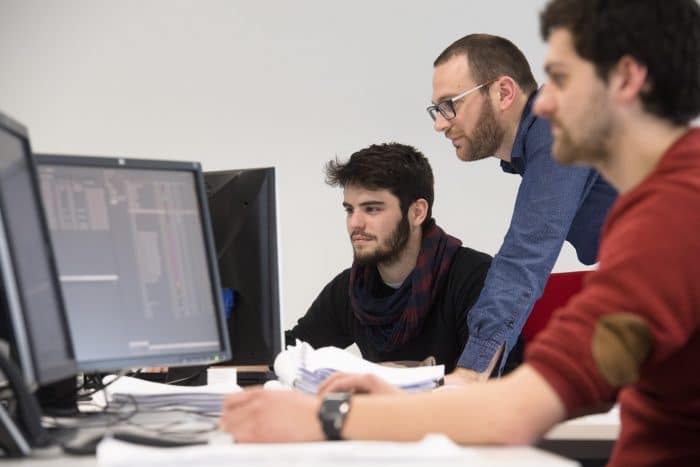 Staff discussing reports on computers