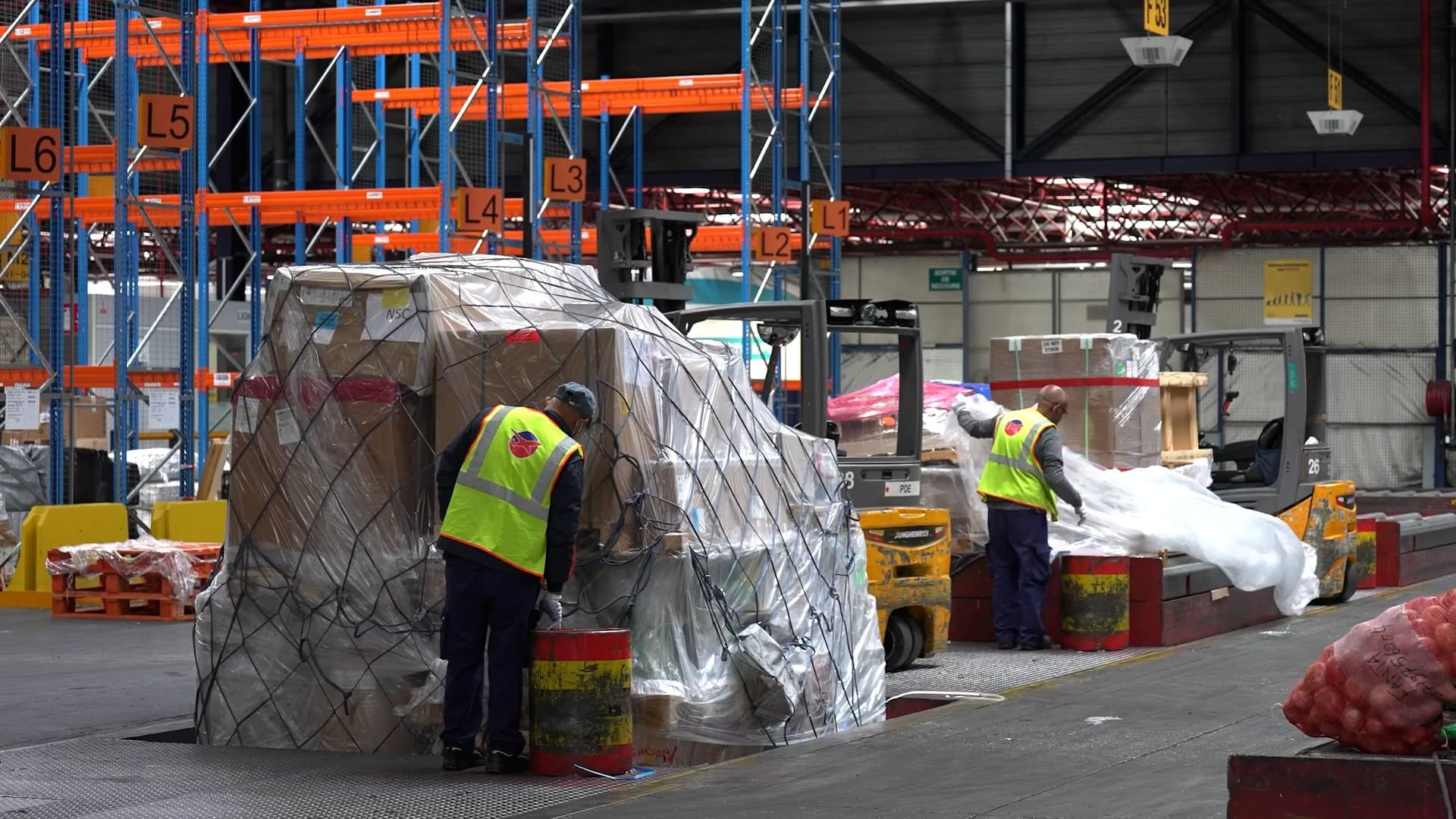 Staff inspecting plastic wrapped pallets