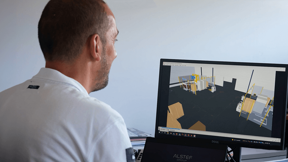 a man in front of a computer with a 3D representation of a warehouse